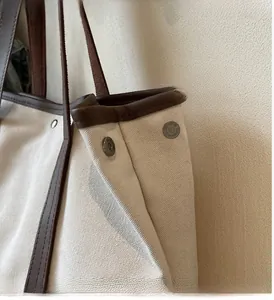 Gros plan d'un sac cabas en toile avec boucle métallique et finitions en cuir brun
