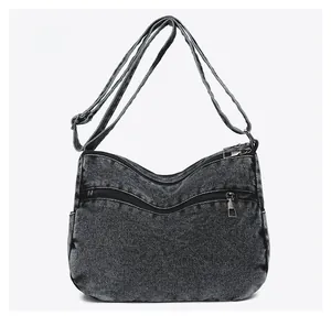 Detailed back view of washed denim crossbody bag featuring multiple zipper pockets