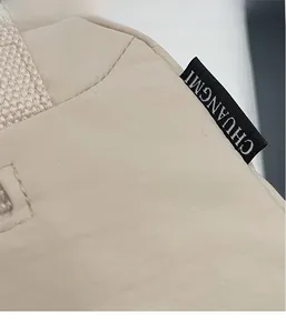 Detail of beige nylon crossbody bag featuring CHUANGMI woven brand label and fine stitching