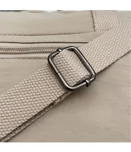 Detail of adjustable metal buckle and woven strap on beige nylon crossbody bag