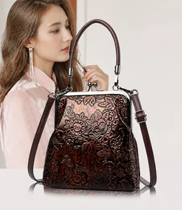 Detalle de bolso vintage marrón rojizo con grabados florales y cierre metálico elegante