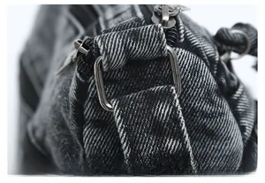 Macro shot of vintage washed denim bag featuring metal zipper and adjustable buckle details