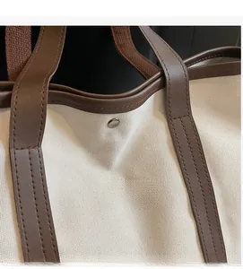 Gros plan du sac fourre-tout en toile crème et cuir marron avec bouton pression