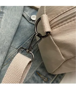 Close-up of beige nylon tote bag featuring a high-quality metal hook and woven shoulder strap