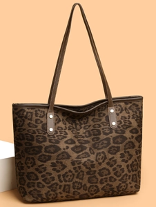 Close-up of leopard print tote bag with brown leather handles and metal rivet details