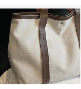 Détail du sac cabas en toile crème avec garniture en cuir marron et rivet métallique