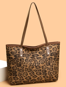 Detail of leopard print tote bag featuring brown leather straps and silver metal rivets