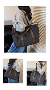 Détail d'un grand sac cabas en toile noire avec anses en cuir marron et boutons pression