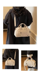 Detail view of large cream crossbody tote with adjustable strap and side zipper pockets