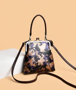 Detalle de bolso vintage marrón con relieve floral y cierre de marco metálico