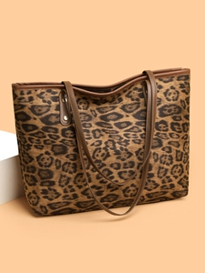 Detail of leopard print tote bag featuring canvas texture and brown leather trim accents