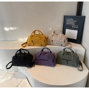 Five assorted crossbody bags in yellow, white, black, purple, and green on display