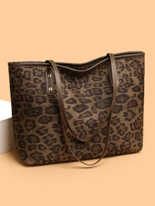 Detail view of large leopard print tote bag with brown leather handles and metal rivets