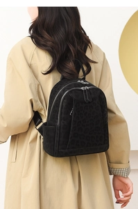 Detail of black leopard print backpack on a model wearing a trench coat