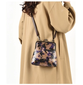 Bolso retro con cierre de boquilla y flores púrpuras usado con gabardina beige
