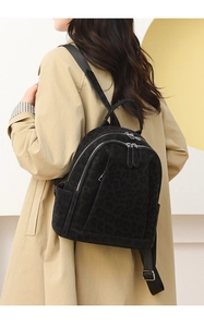 Detail of leopard print backpack texture and silver zippers on a beige trench coat