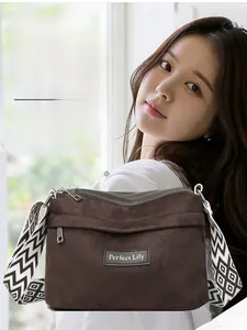 Detail of dark brown crossbody bag with multi-zipper pockets and geometric strap