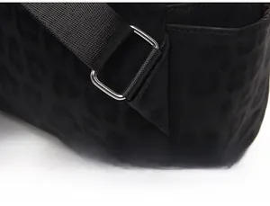Detail of reinforced shoulder strap stitching and metal adjustment buckle on leopard backpack
