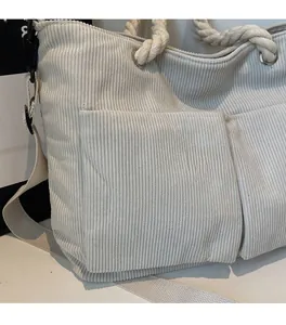 Detail of corduroy tote bag showing large front pockets and durable cotton rope handles