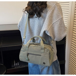 Close-up of light green nylon crossbody bag showing the side logo and fabric texture