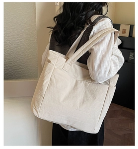 Detail showing high-capacity beige quilted tote bag with wide shoulder straps on a model