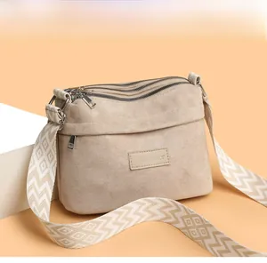 Detail of beige nylon pillow bag featuring a wide geometric pattern strap and brand logo