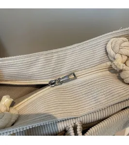 Detail of silver metal zipper and cotton rope handle on beige corduroy tote bag