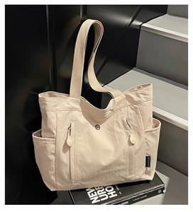 Detail of waterproof nylon tote bag with functional vertical zip pockets and side brand label