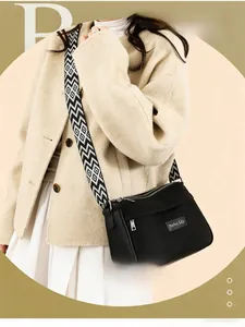 Detail of black leather shoulder bag featuring a geometric patterned woven strap