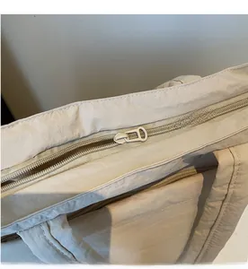 Close-up of smooth matching zipper and durable nylon texture on casual cream tote bag