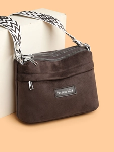 Detail view of multi-pocket brown suede crossbody bag with geometric pattern wide strap