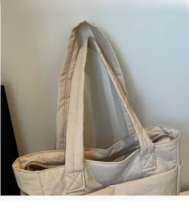 Close-up of durable reinforced stitching and metal zipper on beige casual tote bag