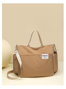 Detail of khaki nylon tote bag featuring front pockets and adjustable crossbody strap