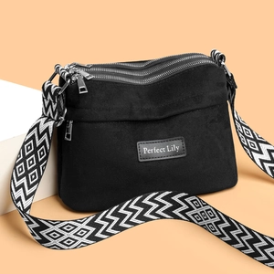 Minimalist black nylon crossbody pillow bag with wide geometric strap and triple zippers