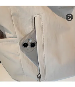 Detail of waterproof nylon tote with side zipper pocket holding a large smartphone