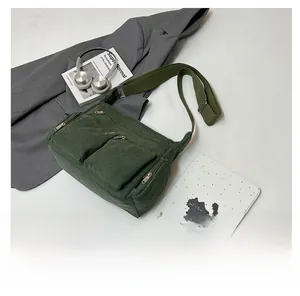 Détail du sac à bandoulière en velours côtelé vert foncé avec deux poches zippées devant