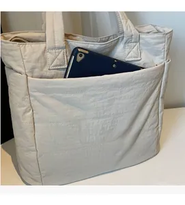 Detailed view of beige nylon tote bag capacity showing a tablet in the front pocket