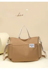 Close-up of khaki nylon shoulder bag showing multi-pocket design and adjustable strap