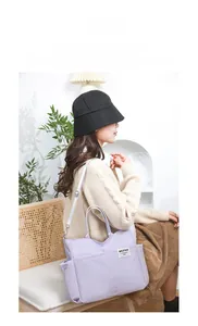 Lifestyle view of a purple nylon tote bag with functional pockets and adjustable strap