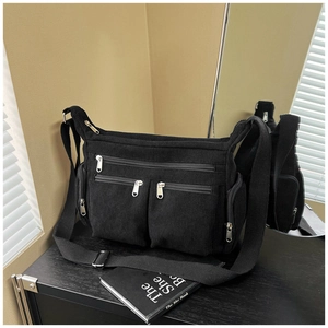 Détail du sac bandoulière en velours côtelé noir avec plusieurs poches zippées et sangle