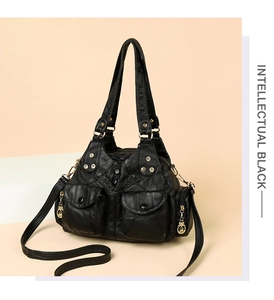 Detail of black soft leather crossbody bag with silver rivets and dual zipper pockets