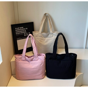 Three oversized quilted tote bags in pink, beige, and black with wide shoulder straps