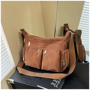 Détail d'un sac bandoulière en velours côtelé marron avec plusieurs poches zippées