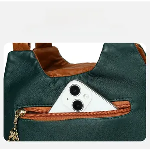 Detailed view of the back zipper pocket on a color-block leather bag with a phone inside