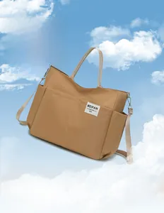 Lightweight khaki nylon shoulder bag with multi-pocket design against a blue sky background