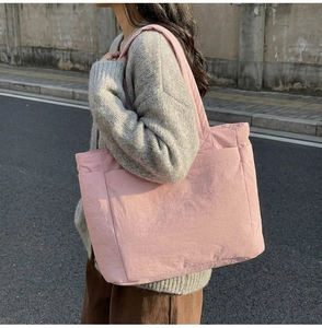 Detail of pink quilted tote bag with side pocket shown in casual street style