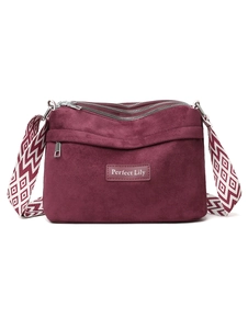 Detail of burgundy suede shoulder bag with triple top zippers and patterned strap