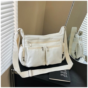 Détail d'un sac cabas en velours côtelé blanc avec multiples poches et bandoulière