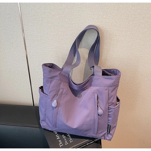 Detail of light purple nylon tote bag featuring vertical zippers and side pockets