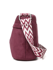 Detail of burgundy crossbody bag with patterned wide strap and silver metal buckle